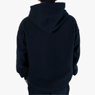 Back view of a model wearing a plain black hoodie from Noir Complete, showcasing the fit and design of the hoodie without any graphics, against a white background.