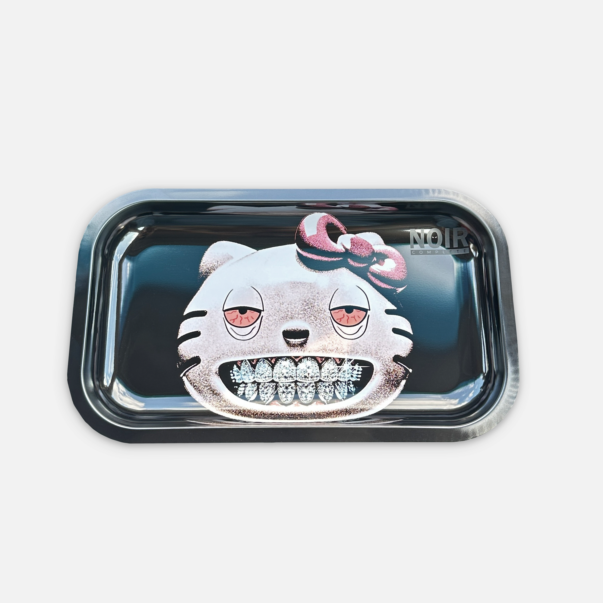 Black rolling tray with a graphic printed showing a light pink cat with a dark pink bow on the left side of its head, with blue diamond grillz and droopy red eyes. There is a logo that shows "noir complete" on the right of the tray in matte black.