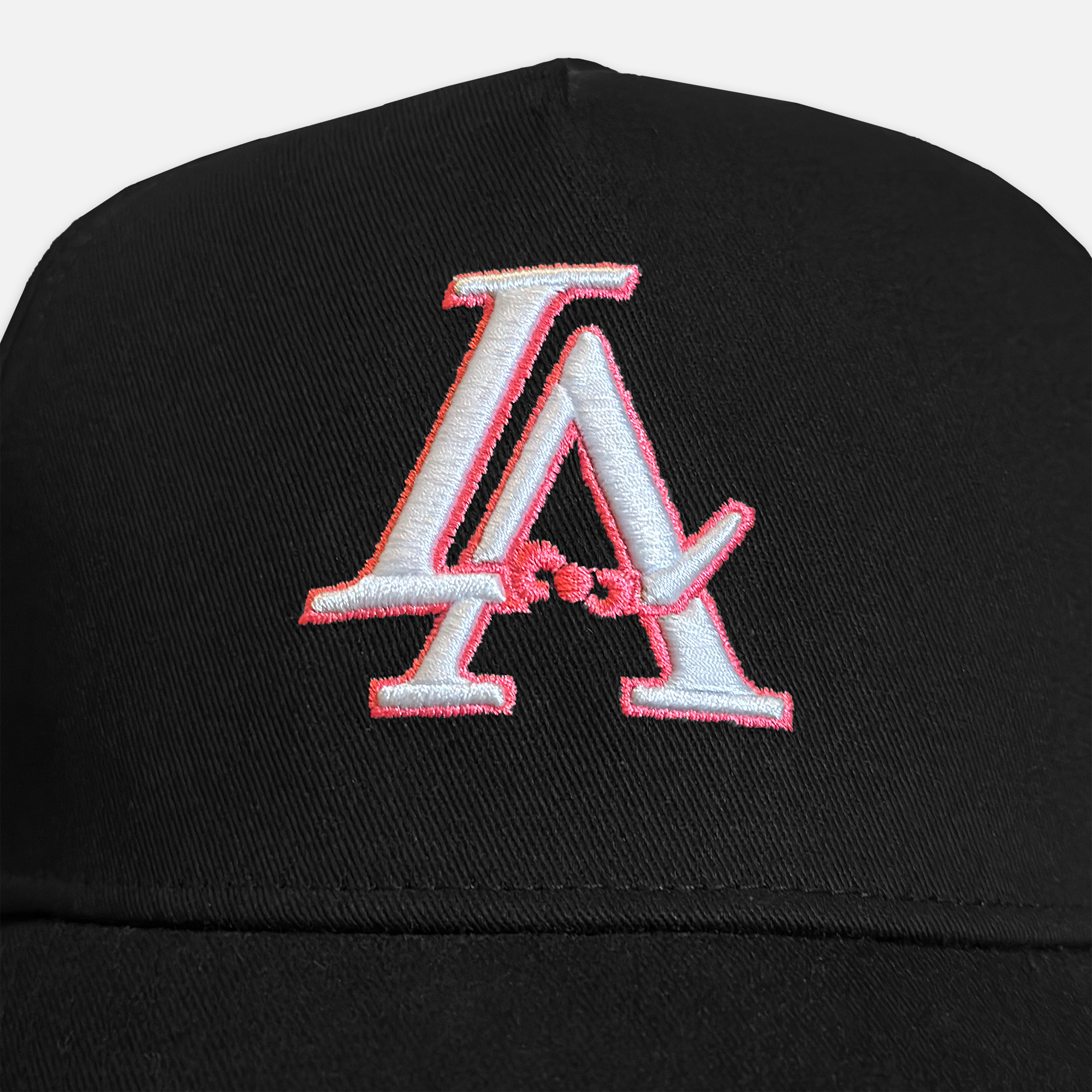 Close up shot of the la bow hat's embroidery, showcasing the white la logo with a pink outline on a black hat.